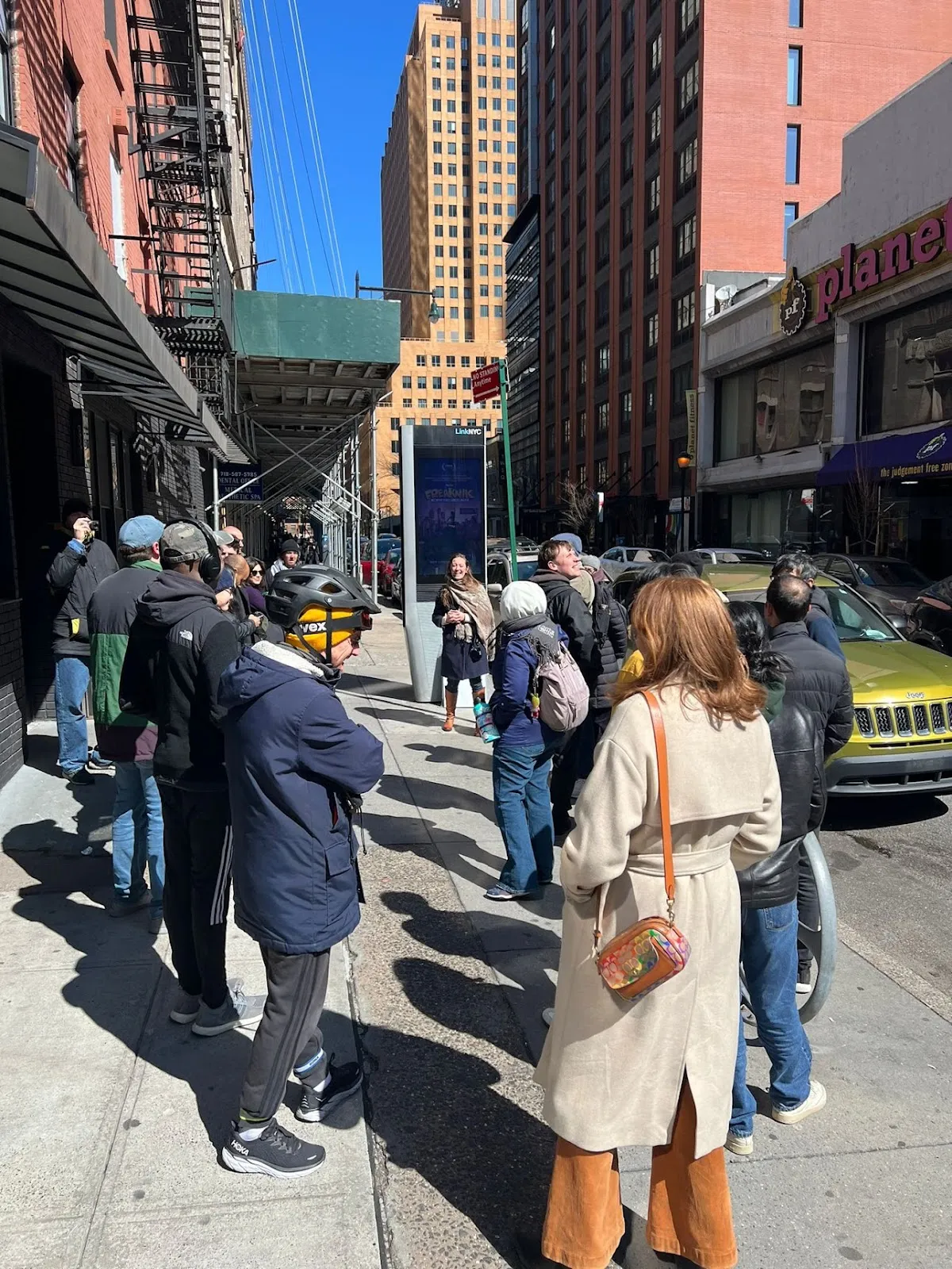 Adrienne Schmoeker of Helpful Places engaging the Downtown Brooklyn tour in discussion around a LinkNYC kiosk